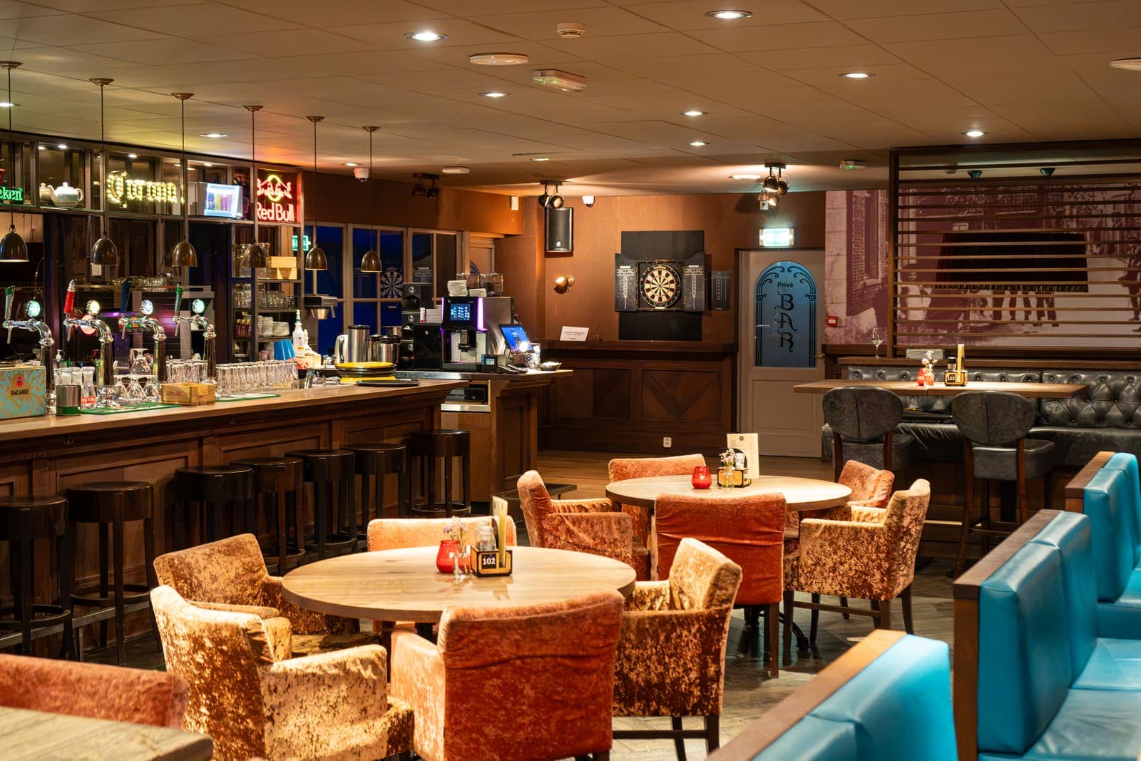 De bar van het Grand Café met tafels en fluwelen stoelen ervoor