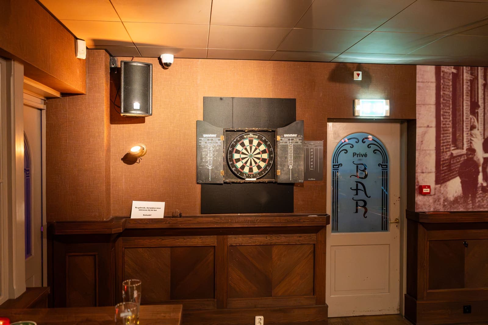 Het dartbord aan de wand van het Grand Café, naast de deur van de privébar