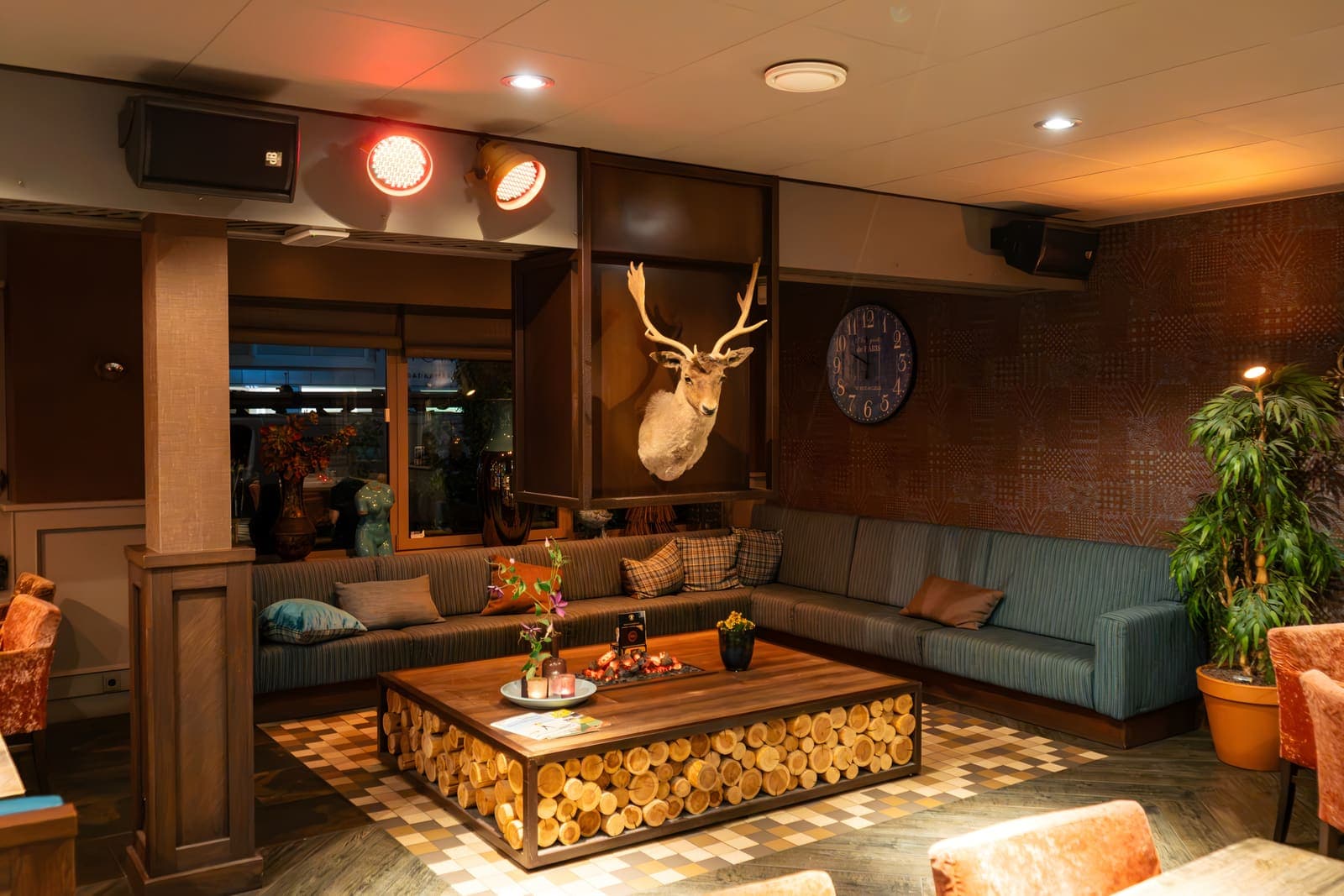 De lounge in het Grand Café: een hoekbank om een salontafel van houtblokken, onder een hertenkop
