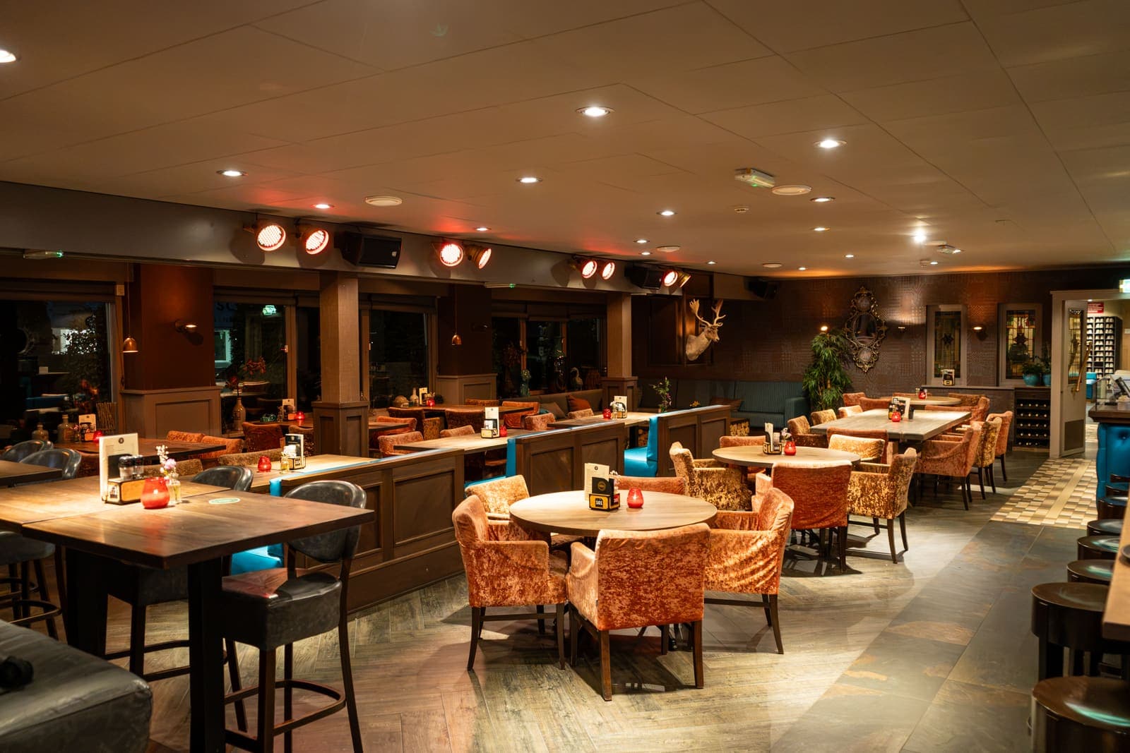 Het Grand Café in de avond, met tafels en fauteuils verspreid door de ruimte
