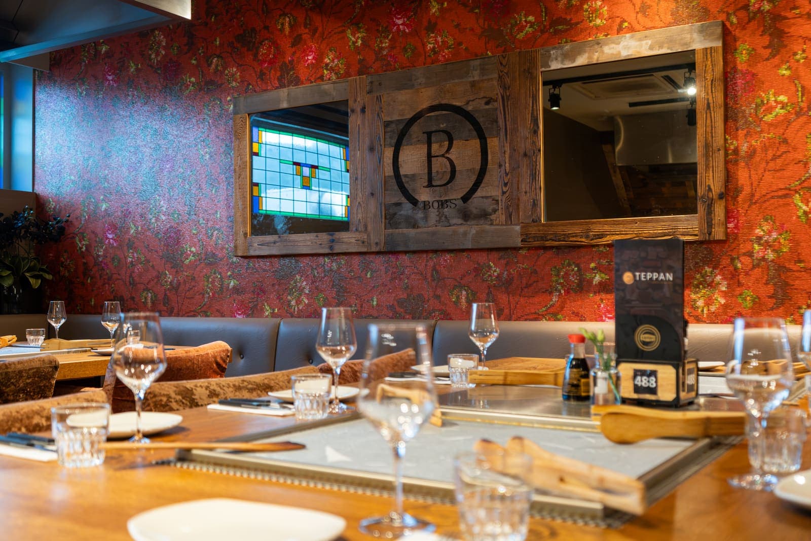 De wand met glas-in-lood en het B-logo boven een gedekte tafel